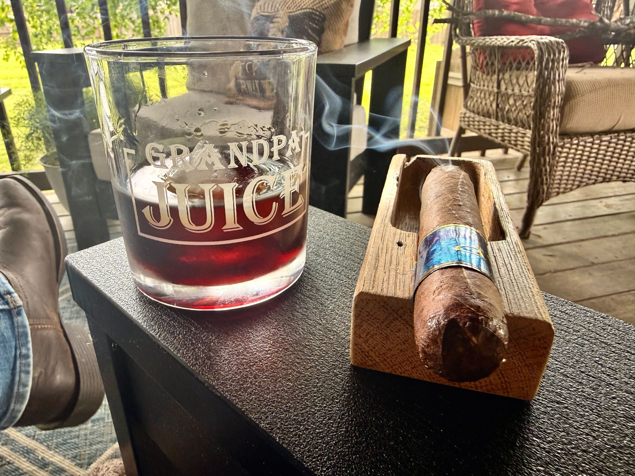 Cigar resting beside a drink on a porch